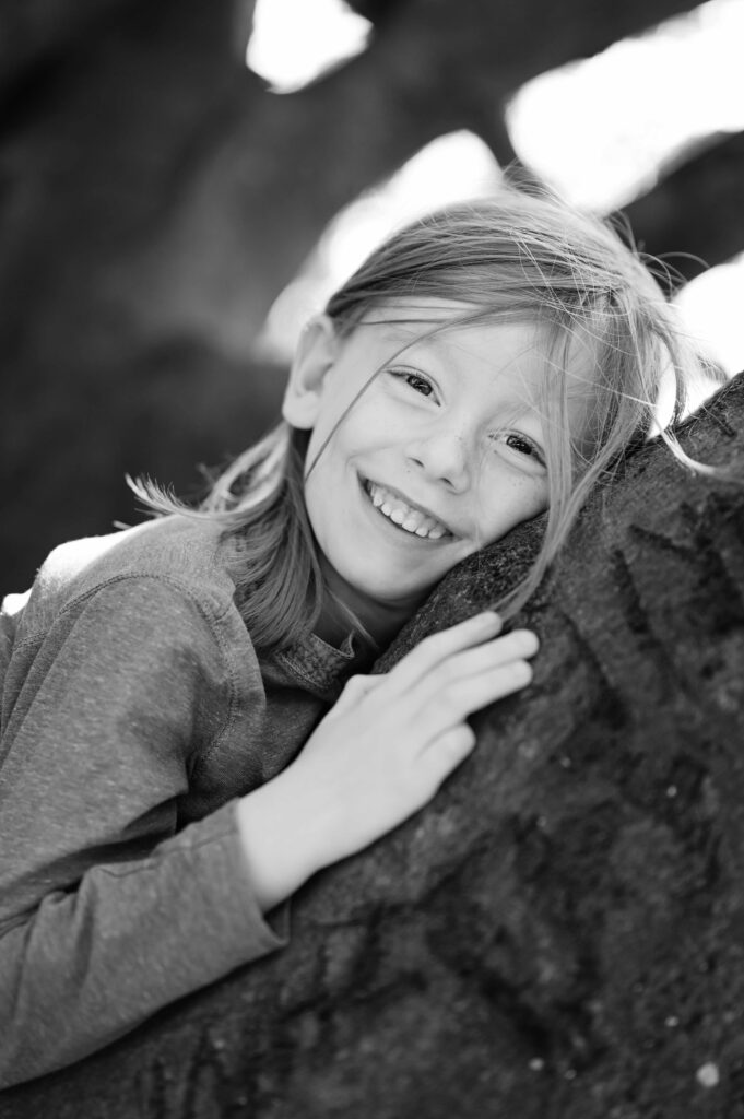 Junge auf Baumstamm liegend beim Familien-Shooting