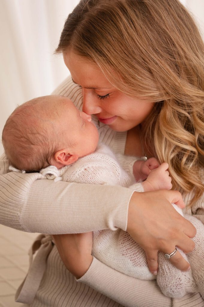 Mama mit Neugeborenem im Arm Nase an Nase beim Neugeborenen-Shooting